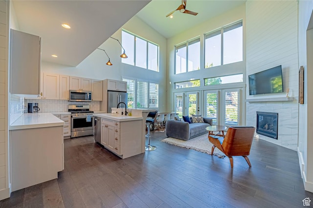 kitchen featuring dark wood-style floors, light countertops, appliances with stainless steel finishes, open floor plan, and an island with sink