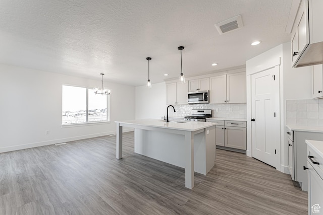 13719 S Devers Dr Unit 2106, Riverton, UT 84096 - kitchen featuring stainless steel appliances, a chandelier, a sink, a textured ceiling, and light wood-type flooring
