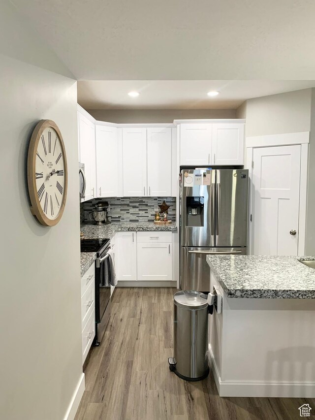 1999 E Abbey Way, Eagle Mountain, UT 84005 - kitchen with tasteful backsplash, appliances with stainless steel finishes, light stone counters, wood finished floors, and white cabinetry