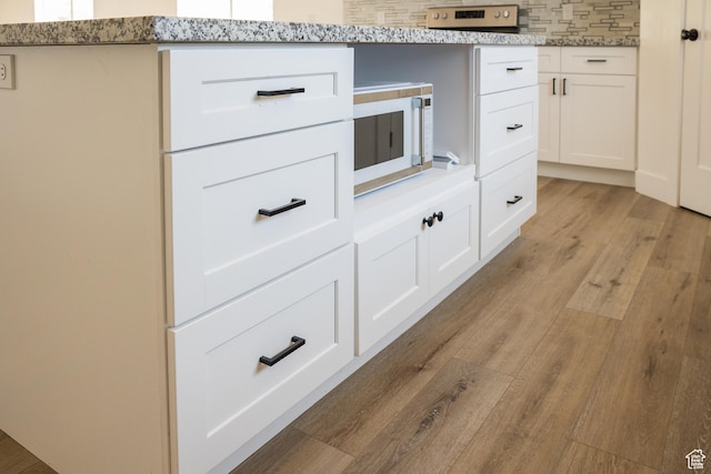 2159 W 520 S, Roosevelt, UT 84066 - kitchen view of white microwave, light wood-style floors, white cabinetry, backsplash, and light stone countertops