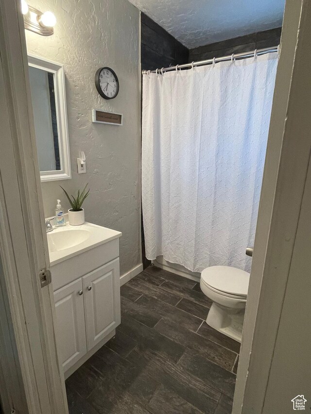 431 Circle Way, Sunnyside, UT 84539 - bathroom with curtained shower, hardwood / wood-style floors, vanity, toilet, and a textured ceiling