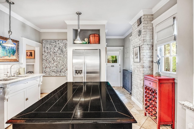 kitchen with sink, light stone counters, ornamental molding, stainless steel appliances, and white cabinets