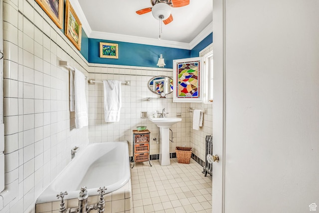 bathroom with ornamental molding, sink, tile walls, and a tub to relax in