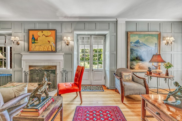living area featuring light hardwood / wood-style flooring, a tile fireplace, and french doors