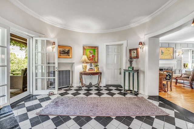 entrance foyer with a tiled fireplace, crown molding, and radiator heating unit