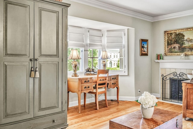living area with a tiled fireplace, light hardwood / wood-style flooring, and ornamental molding