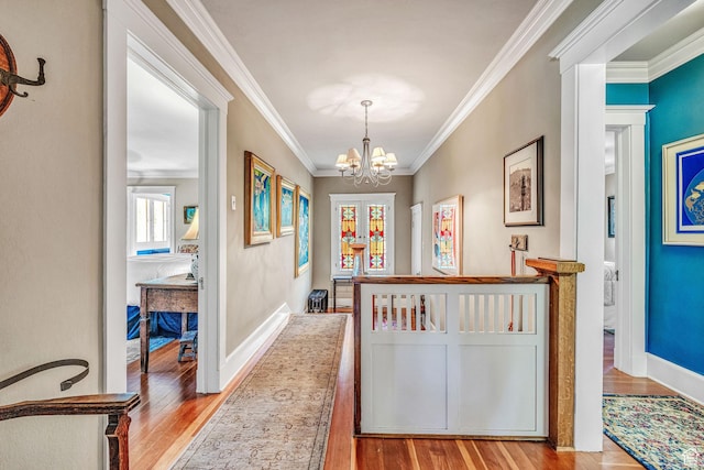 hall featuring crown molding, a chandelier, and light wood-type flooring