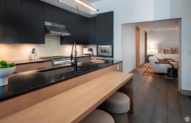 1271 Lowell Ave Unit B-103, Park City, UT 84060 - kitchen featuring range hood, modern cabinets, stainless steel oven, dark cabinetry, and a kitchen breakfast bar