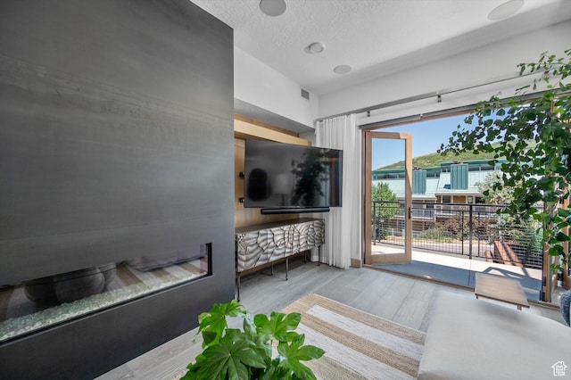 1271 Lowell Ave Unit B-103, Park City, UT 84060 - living area featuring visible vents, wood finished floors, a glass covered fireplace, and a textured ceiling