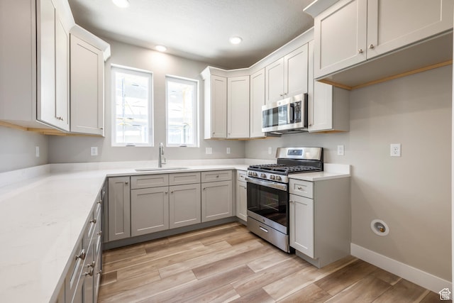 1072 S 2760 E, Spanish Fork, UT 84660 - kitchen with gray cabinets, light wood-type flooring, sink, light stone counters, and appliances with stainless steel finishes