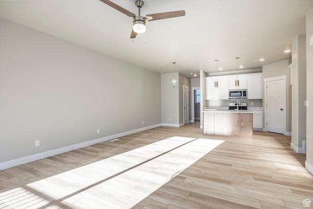 1068 S 2760 E, Spanish Fork, UT 84660 - kitchen featuring range, white cabinets, a center island with sink, light hardwood / wood-style floors, and ceiling fan