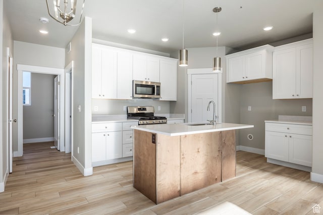 1068 S 2760 E, Spanish Fork, UT 84660 - kitchen with appliances with stainless steel finishes, decorative light fixtures, a kitchen island with sink, light wood-type flooring, and white cabinetry