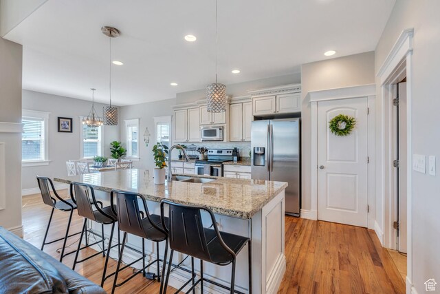 kitchen featuring pendant lighting, sink, a large island, stainless steel appliances, and light stone countertops
