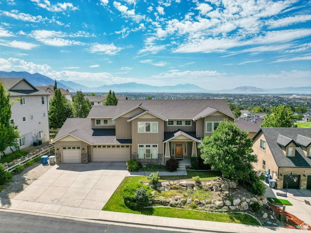 view of front facade with an attached garage, driveway, a mountain view, and stone siding