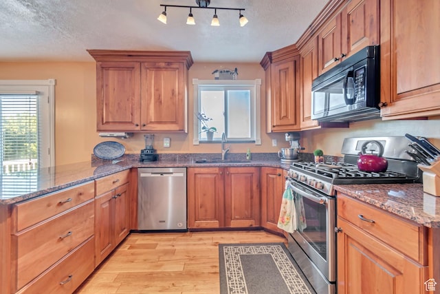 751 W 3500 N, Pleasant View, UT 84414 - kitchen featuring dark stone countertops, sink, light hardwood / wood-style flooring, and appliances with stainless steel finishes