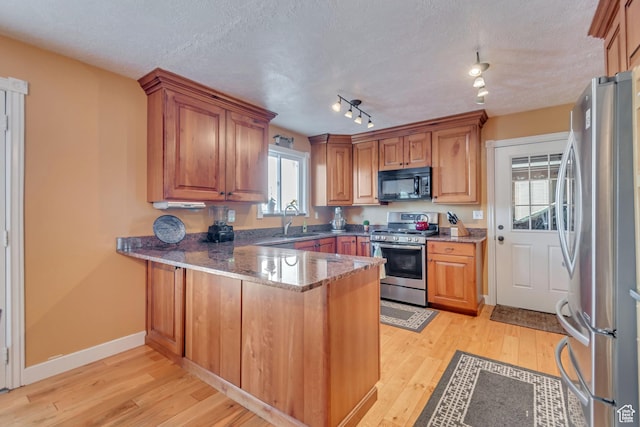 751 W 3500 N, Pleasant View, UT 84414 - kitchen with sink, stainless steel appliances, kitchen peninsula, dark stone counters, and light wood-type flooring