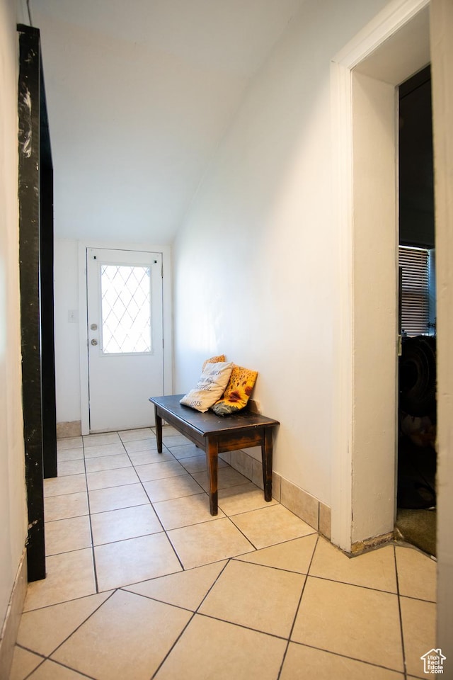 corridor with lofted ceiling and light tile patterned floors