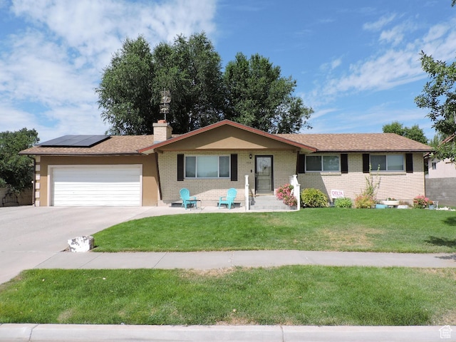 325 N 100 W, Delta, UT 84624 - ranch-style home with a chimney, an attached garage, a front lawn, brick siding, and roof mounted solar panels