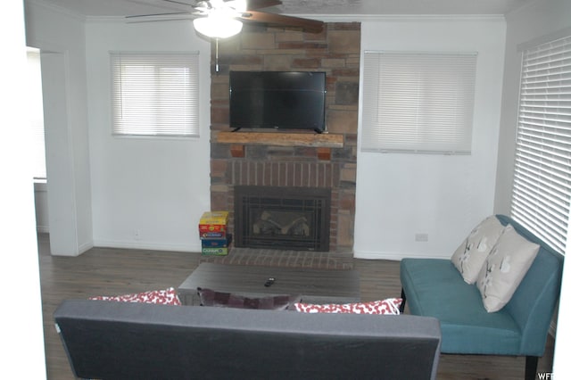 living room featuring baseboards, ornamental molding, ceiling fan, wood finished floors, and a large fireplace