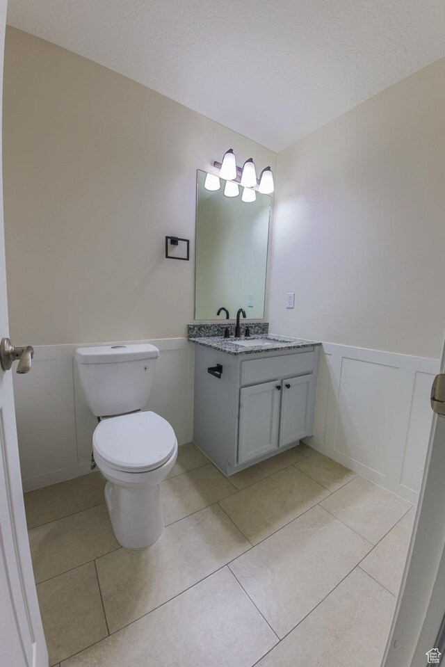 1279 W Culloden Ct, Murray, UT 84123 - half bath with toilet, a wainscoted wall, tile patterned floors, vanity, and a decorative wall