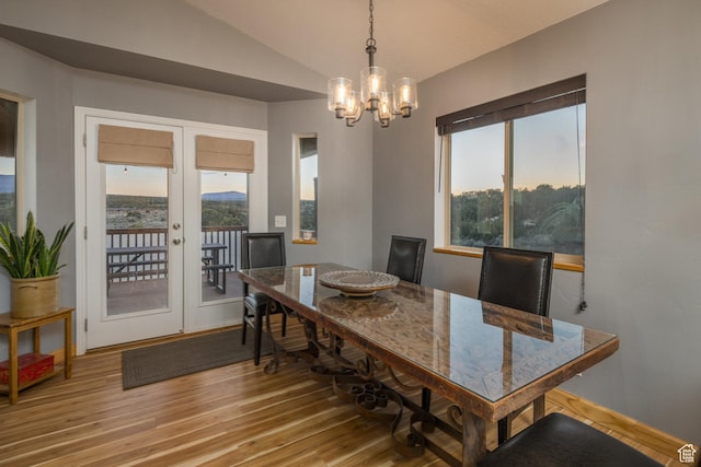 dining area with a wealth of natural light, light wood-type flooring, lofted ceiling, and a notable chandelier