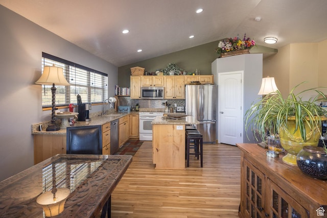kitchen with light wood-type flooring, light brown cabinets, a center island, appliances with stainless steel finishes, and lofted ceiling