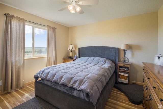 bedroom featuring ceiling fan, baseboards, and wood finished floors