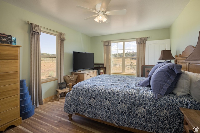 bedroom featuring baseboards, wood finished floors, and a ceiling fan