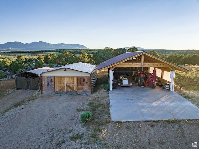 view of front facade with a mountain view, an outbuilding, a carport, and driveway