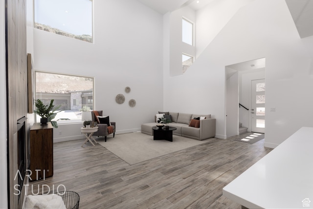 living room with light wood-type flooring, a high ceiling, and a wealth of natural light