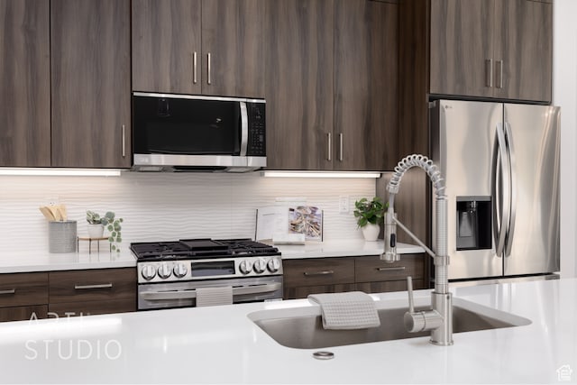 kitchen with stainless steel appliances, sink, dark brown cabinets, and backsplash