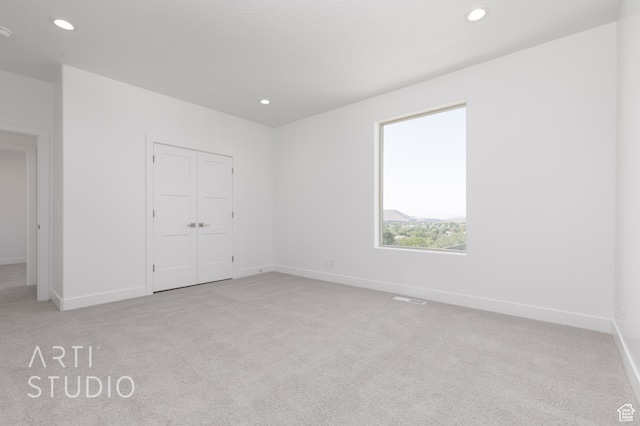unfurnished bedroom featuring light carpet and a closet