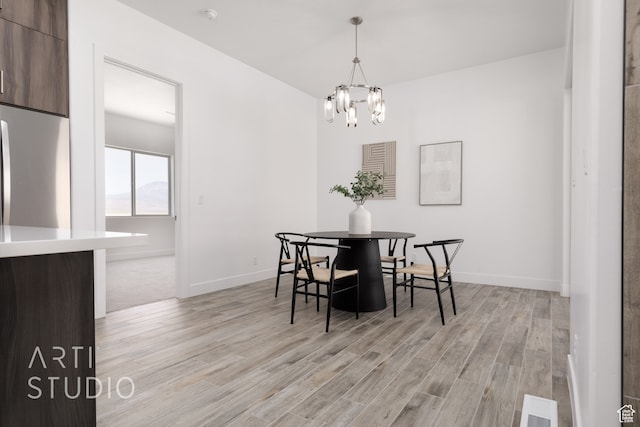dining space with a notable chandelier and light hardwood / wood-style flooring