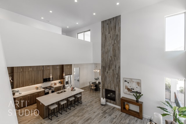 interior space featuring an inviting chandelier, a towering ceiling, sink, and light hardwood / wood-style flooring
