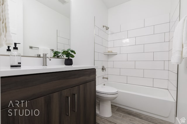 full bathroom featuring hardwood / wood-style flooring, tiled shower / bath, vanity, and toilet
