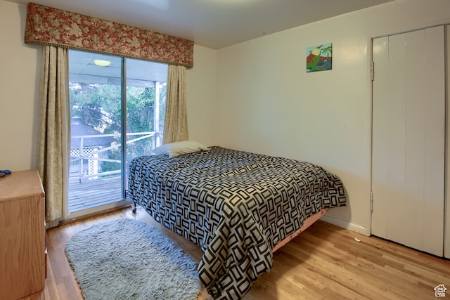 bedroom featuring access to exterior, light wood-type flooring, and a closet