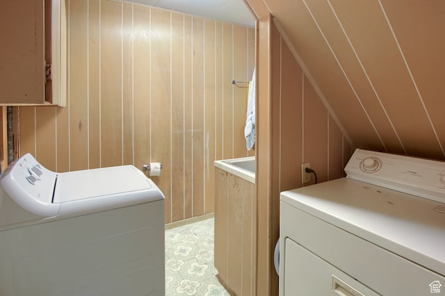 clothes washing area with wood walls and independent washer and dryer