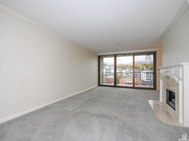 unfurnished living room featuring light carpet, baseboards, a premium fireplace, ornamental molding, and floor to ceiling windows