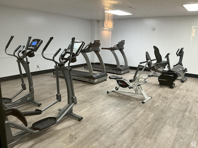 exercise room with baseboards and wood finished floors