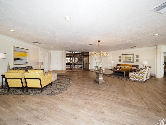 living area featuring a textured ceiling, visible vents, and crown molding