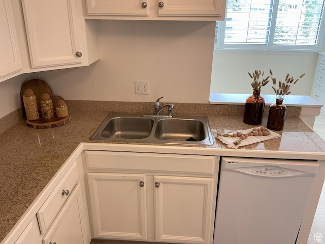 kitchen featuring dishwasher, a peninsula, a sink, and white cabinets