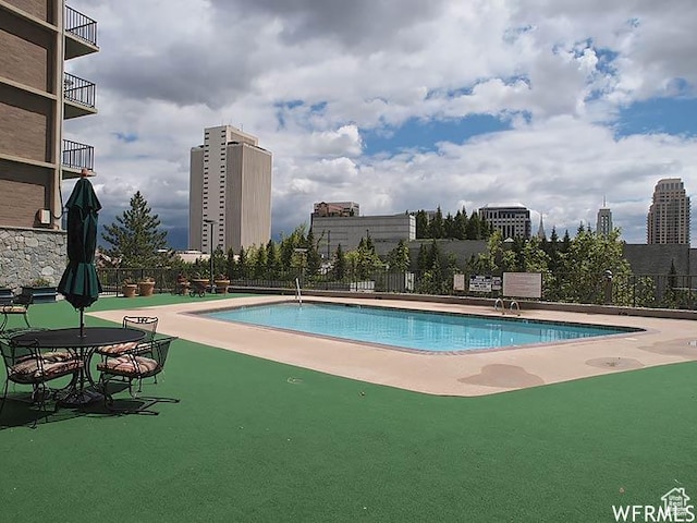 pool with a view of city, a patio, and fence