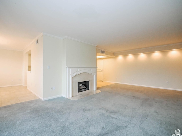 unfurnished living room with carpet, a fireplace with raised hearth, crown molding, and visible vents