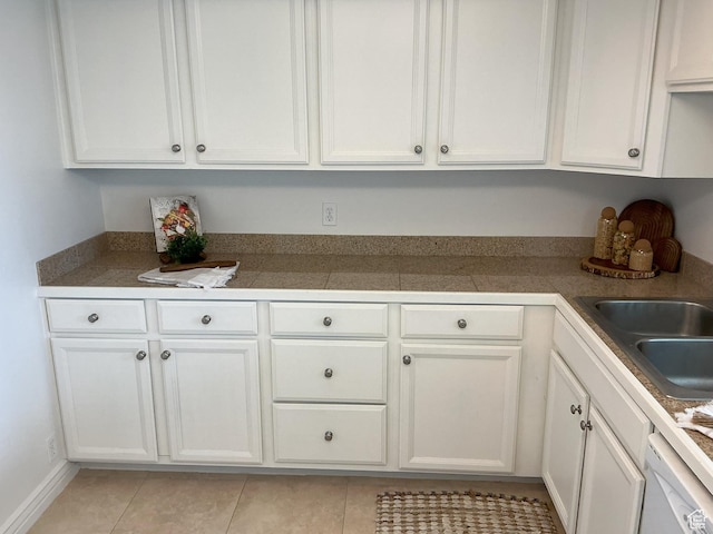 kitchen with tile countertops, light tile patterned floors, a sink, white cabinets, and dishwasher