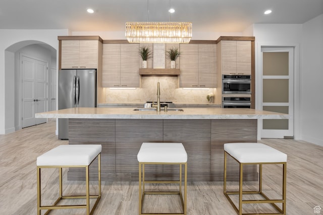 2596 S Gritton St, Hurricane, UT 84737 - kitchen with a kitchen bar, a center island with sink, a sink, backsplash, and stainless steel appliances