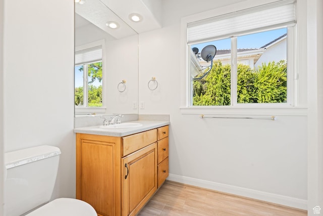bathroom with toilet, baseboards, wood finished floors, and vanity