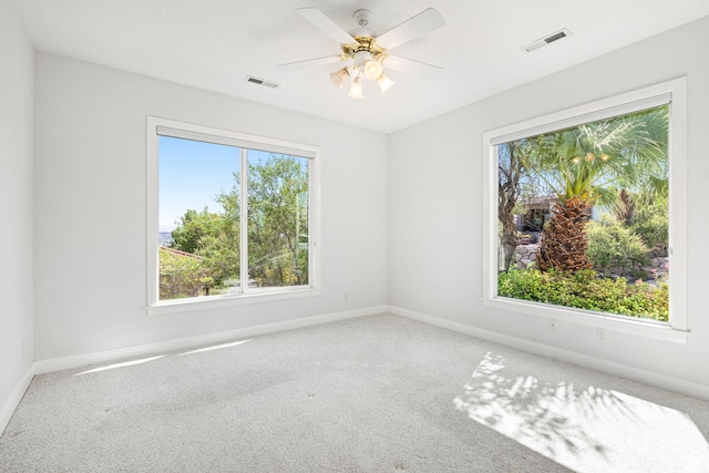 carpeted spare room featuring visible vents, ceiling fan, and baseboards