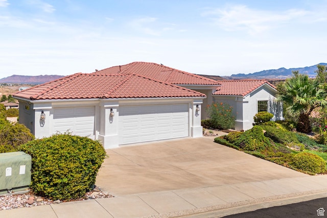 view of front of house with concrete driveway, a tile roof, a mountain view, and stucco siding