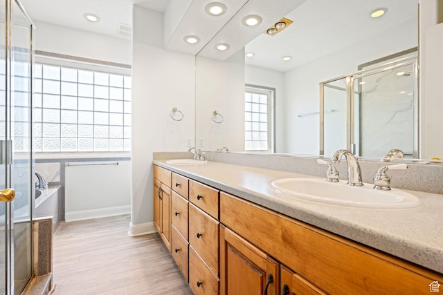 full bathroom featuring double vanity, a stall shower, wood finished floors, a sink, and recessed lighting