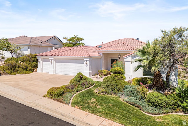 mediterranean / spanish house featuring driveway, an attached garage, a tile roof, and stucco siding